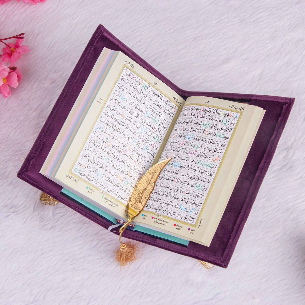 Open Quran with color-coded Tajweed rules and gold feather bookmark. A key feature of the Purple Sequence Rehal Hamper for learners.