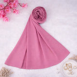 Dark pink studded hijab rolled and displayed on a white surface with floral and pearl accents. Perfect chiffon scarf for elegant modest wear.