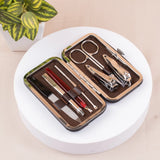 Manicure set with tools in a brown case on a white surface with a plant in the background