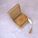 Golden Sequence Mini Tilawat-e-Quran placed inside open velvet designer box with gold feather tassel bookmark beside it, ideal for gifting.
