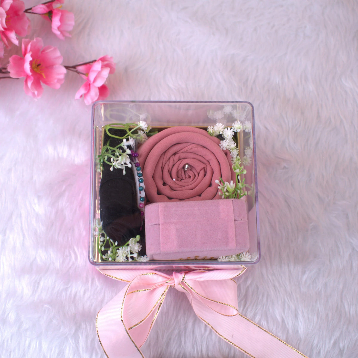 Top view of Pink Hijab Combo showcasing rolled pink hijab, black cap, pink box, and floral accents—perfect for gifting occasions.