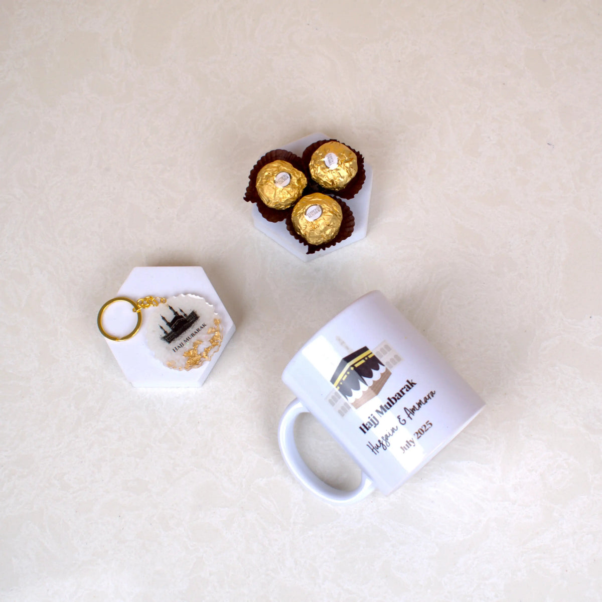 Flat lay of Barakah Blessings Hamper with personalized Hajj Mug, Kaaba keychain, and chocolates. Thoughtful gift for Hajj & Umrah pilgrims.