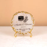 Close-up of personalized Hajj frame with Kaaba artwork and gold stand from Makkah Moments Hamper. Elegant Islamic decor gift item.