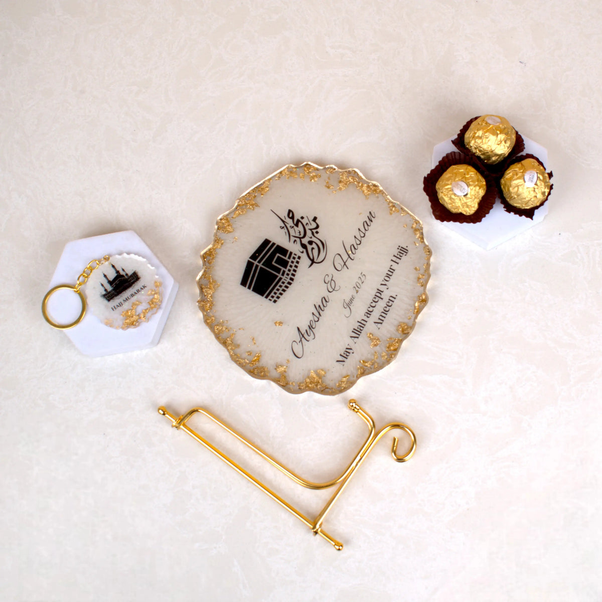 Makkah Moments Hamper with personalized Hajj frame, Tawaf keychain, and Ferrero Rocher chocolates on a marble background. Ideal Islamic gift hamper.