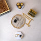 Unboxed Pilgrim's Promise Hamper showing Hajj Mubarak candle, Kaaba frame with gold stand, chocolates, and keychain on a white surface.