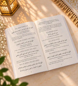 Open book with text on a light surface next to a plant