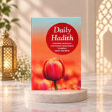 Book titled 'Daily Hadith' with a tulip design on a white surface with books and a plant in the background.