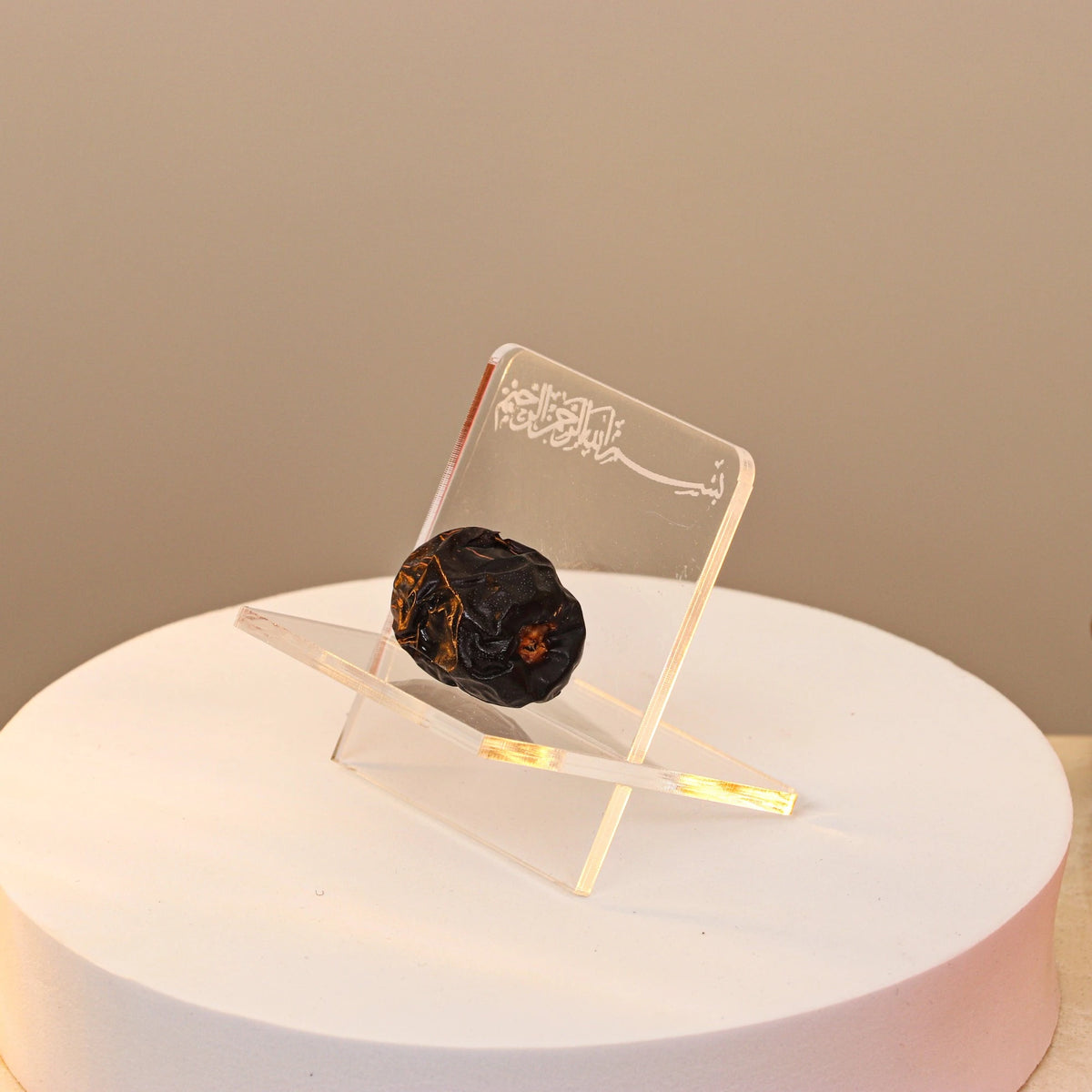 Close-up of Acrylic Date Stand with Bismillah inscription, showcasing a single date for Ramadan, ideal for kitchen and dining decor.