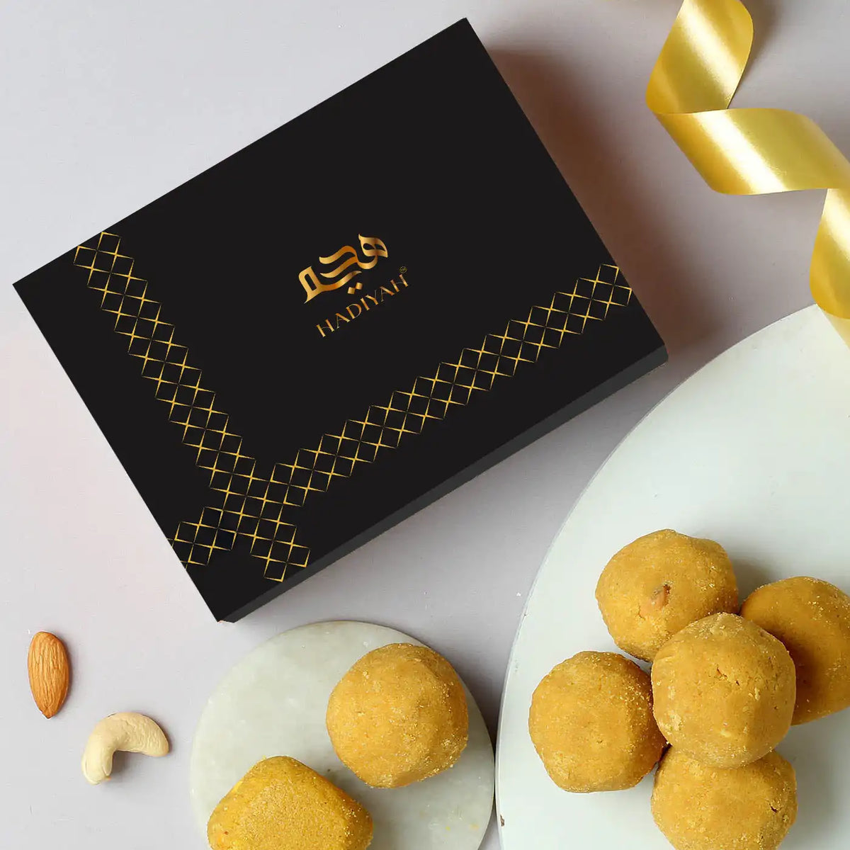 Premium Desi Ghee Besan Laddoo in luxury black and gold packaging, perfect for weddings, Eid, and gourmet gift hampers.