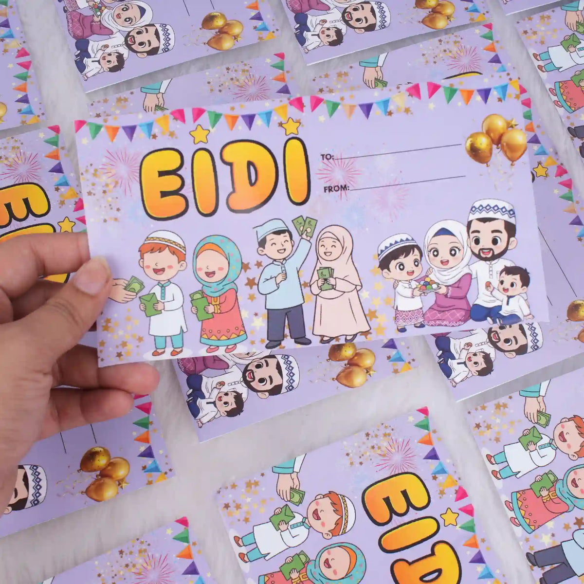 A hand holding a purple Eidi envelope featuring large yellow 'EIDI' text and illustrations of children receiving cash gifts, with several matching envelopes scattered in the background.