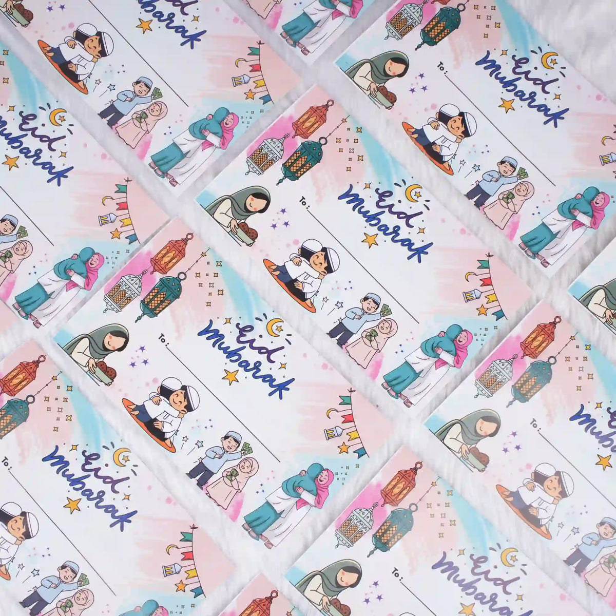 A flat lay view of multiple white Eid Mubarak printed paper envelopes with festive cartoon designs, scattered diagonally across a soft white textured background.