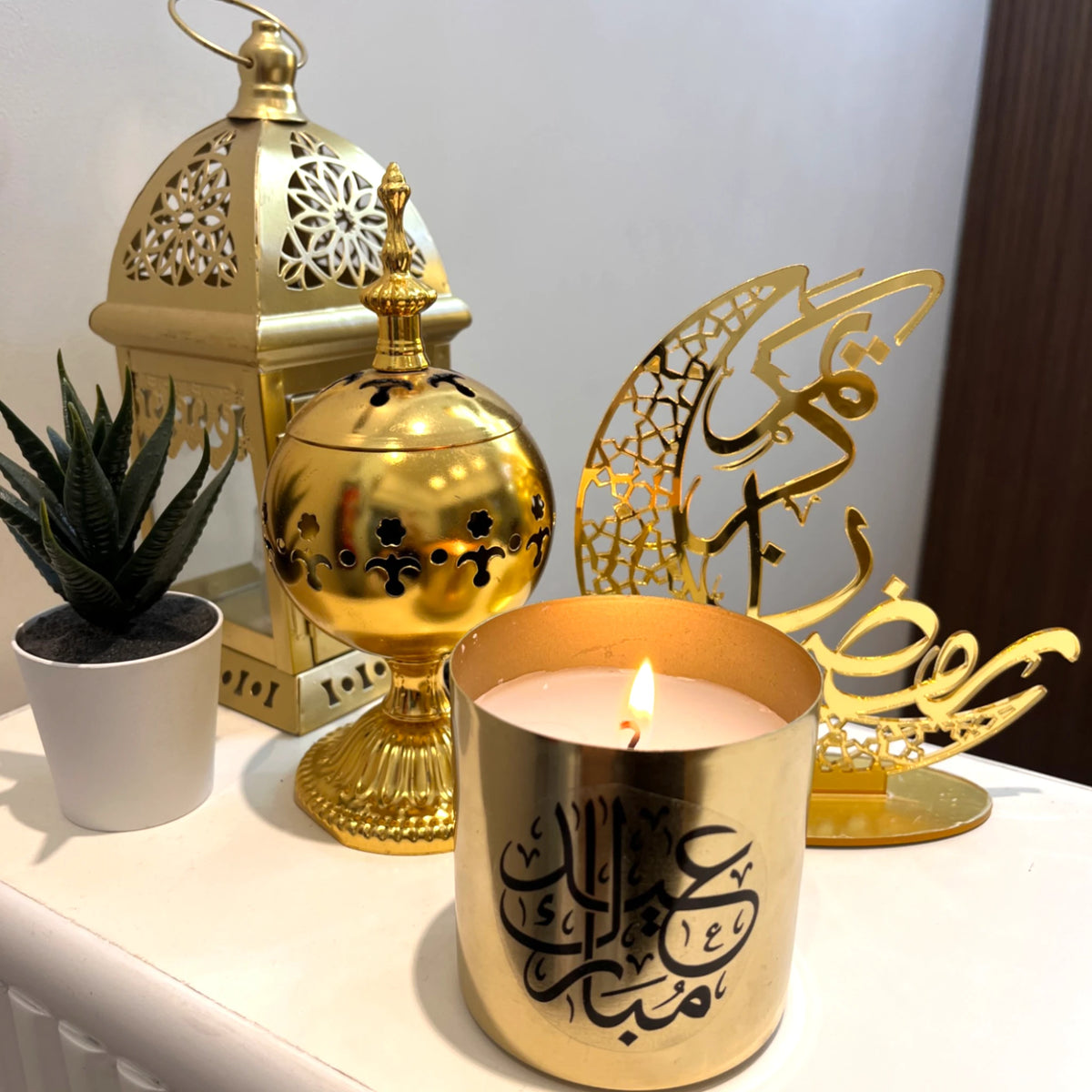 Arabic calligraphy Eid Scented Candle in gold jar, styled with Islamic lanterns and crescent moon decor. Ideal for Eid gifting and ambiance.