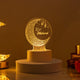 Glowing Eid Mubarak LED acrylic lamp displaying a crescent moon and lantern motif, resting on a white base against a warm, softly lit background.