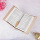 Open book with a decorative gold leaf on a white surface with pink flowers and a gold lantern.