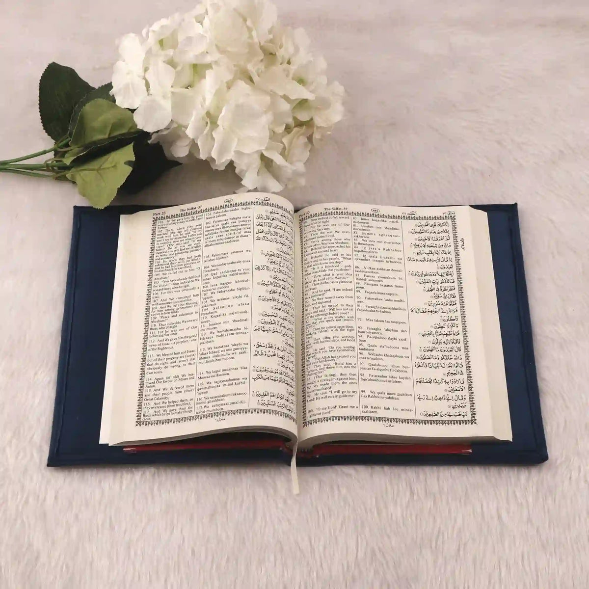 Open book with floral arrangement on a light surface