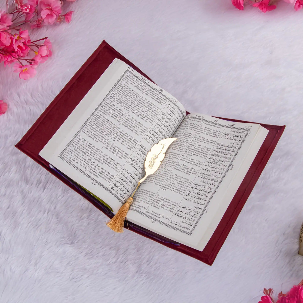 Open book with a decorative bookmark on a light pink background with pink flowers.
