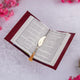 Open book with a decorative bookmark on a light pink background with pink flowers.