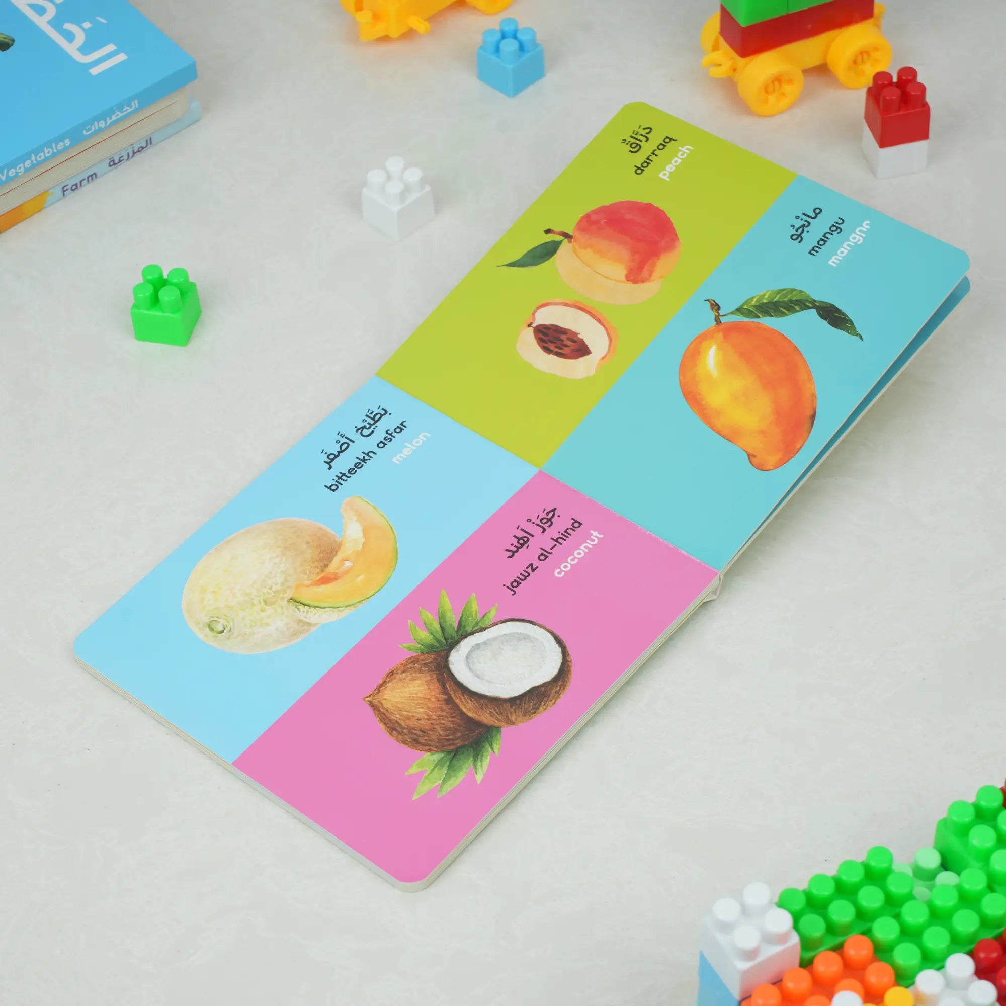 Open Fruits Board Book showing bilingual fruit names like mango and coconut with vivid images, ideal for kids aged 1-4 years.