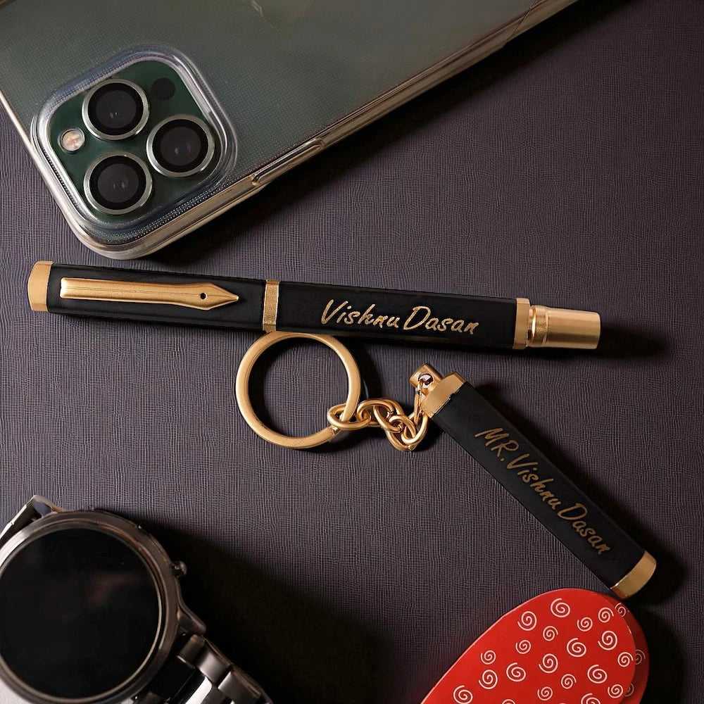Custom engraved black and gold Personalised Pen and Key Chain set beside a smartphone and watch, perfect for executive gifts.