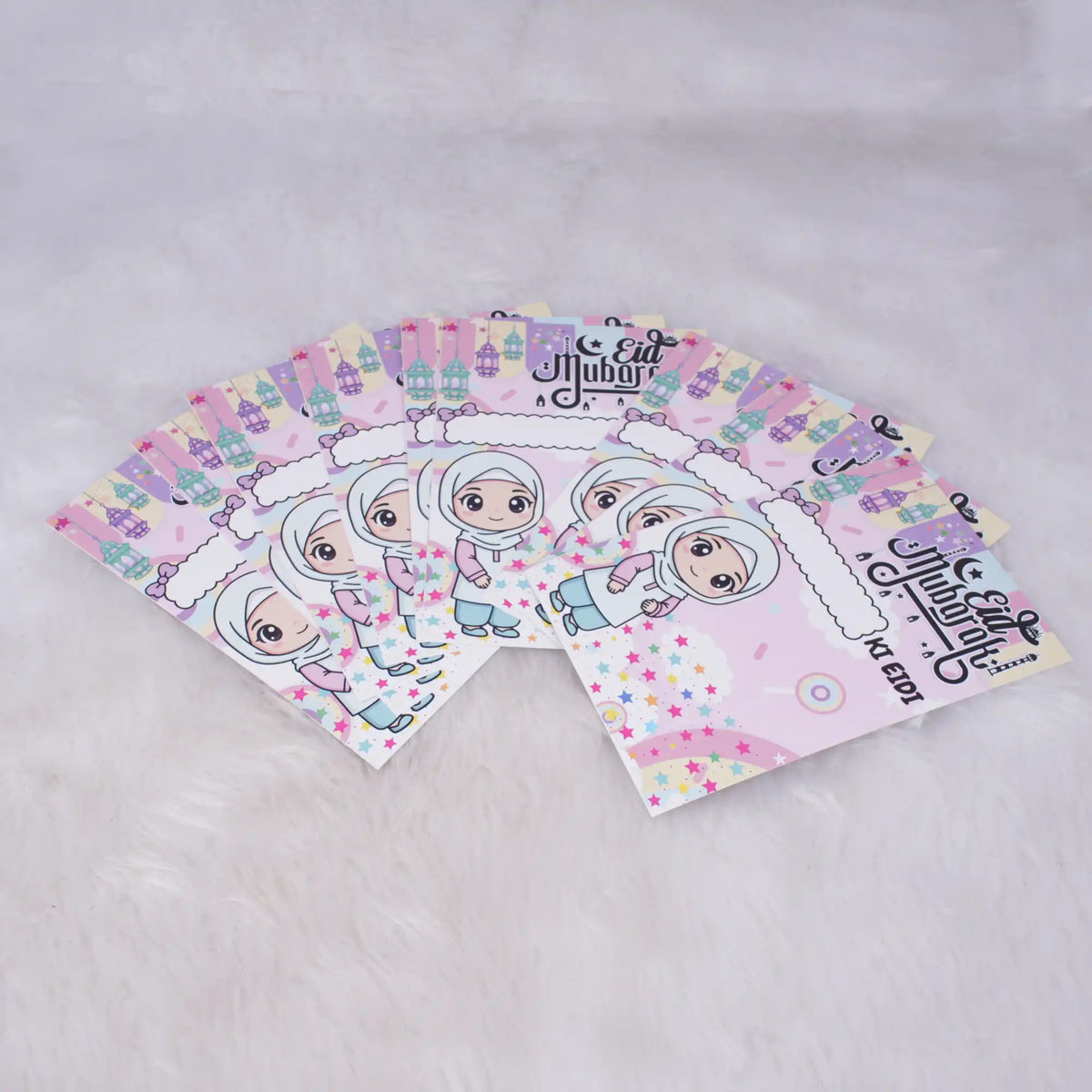 A fanned-out stack of pink Eidi cards for girls featuring a cartoon girl in a hijab, pastel stars, lanterns, and "Eid Mubarak" text.