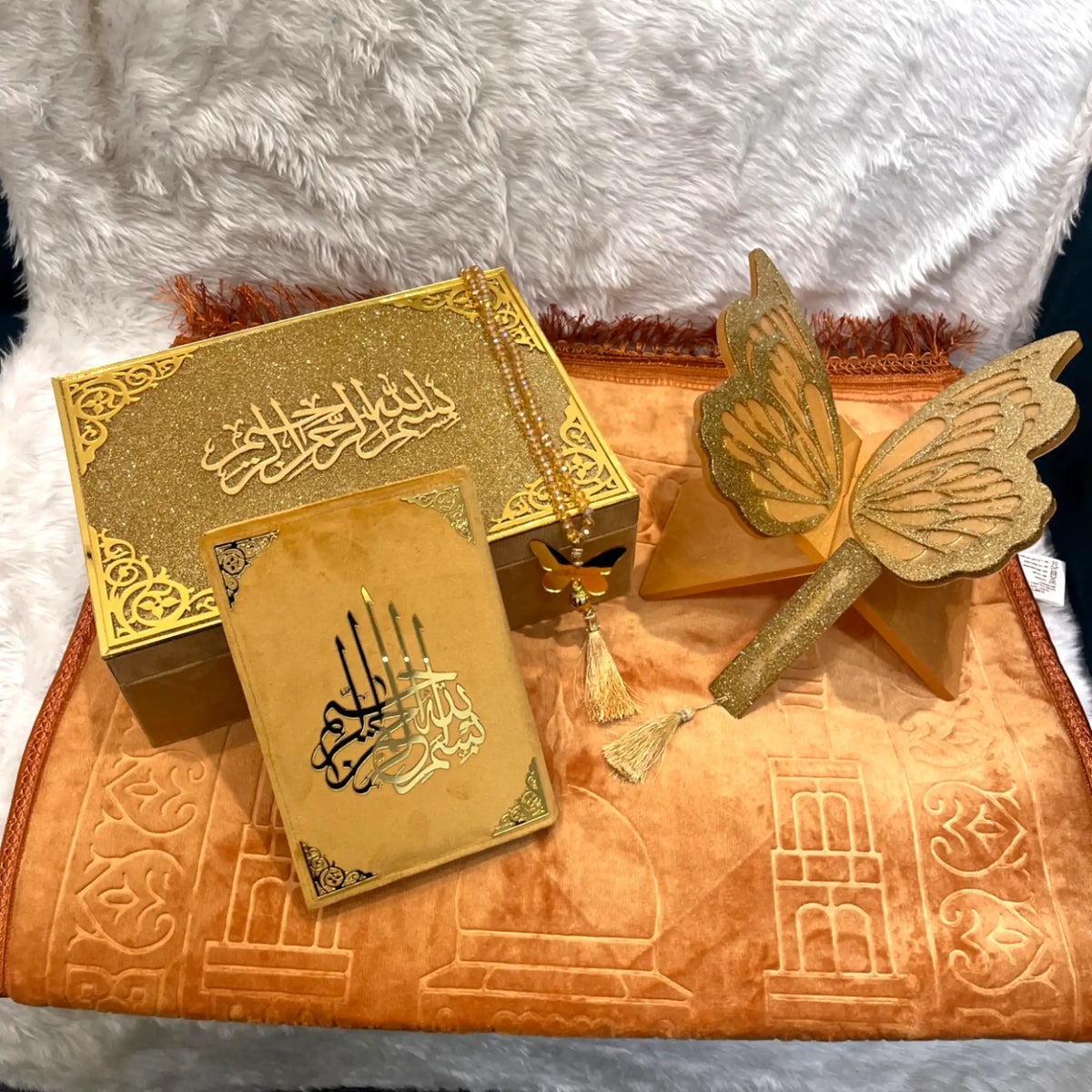 Gold Quranic book with butterfly design on a textured surface