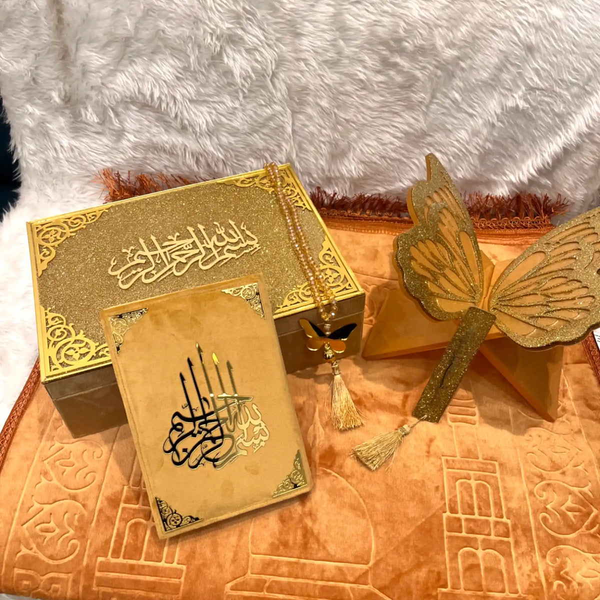 Decorative set with gold box, card, and butterfly on a textured surface