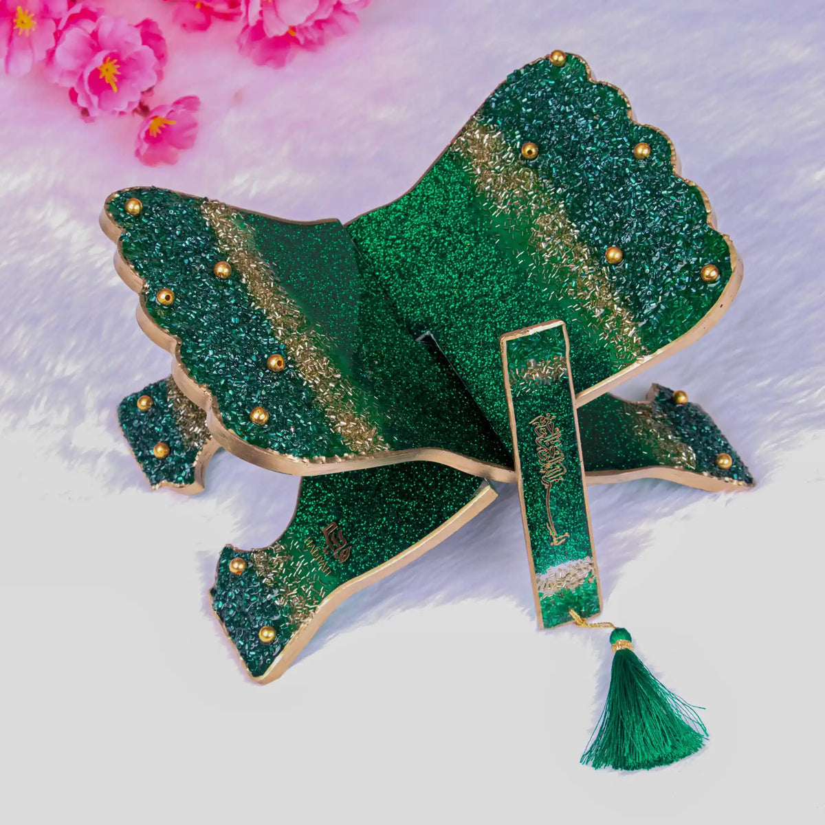 Green glittery brooch with tassel on a light background
