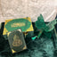 Green and gold decorative items including a butterfly ornament on a textured surface.