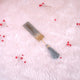 Decorative bookmark with tassel on a soft pink background with small red flowers.