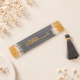 Decorative bookmark with tassel on a fluffy white surface with pink flowers.