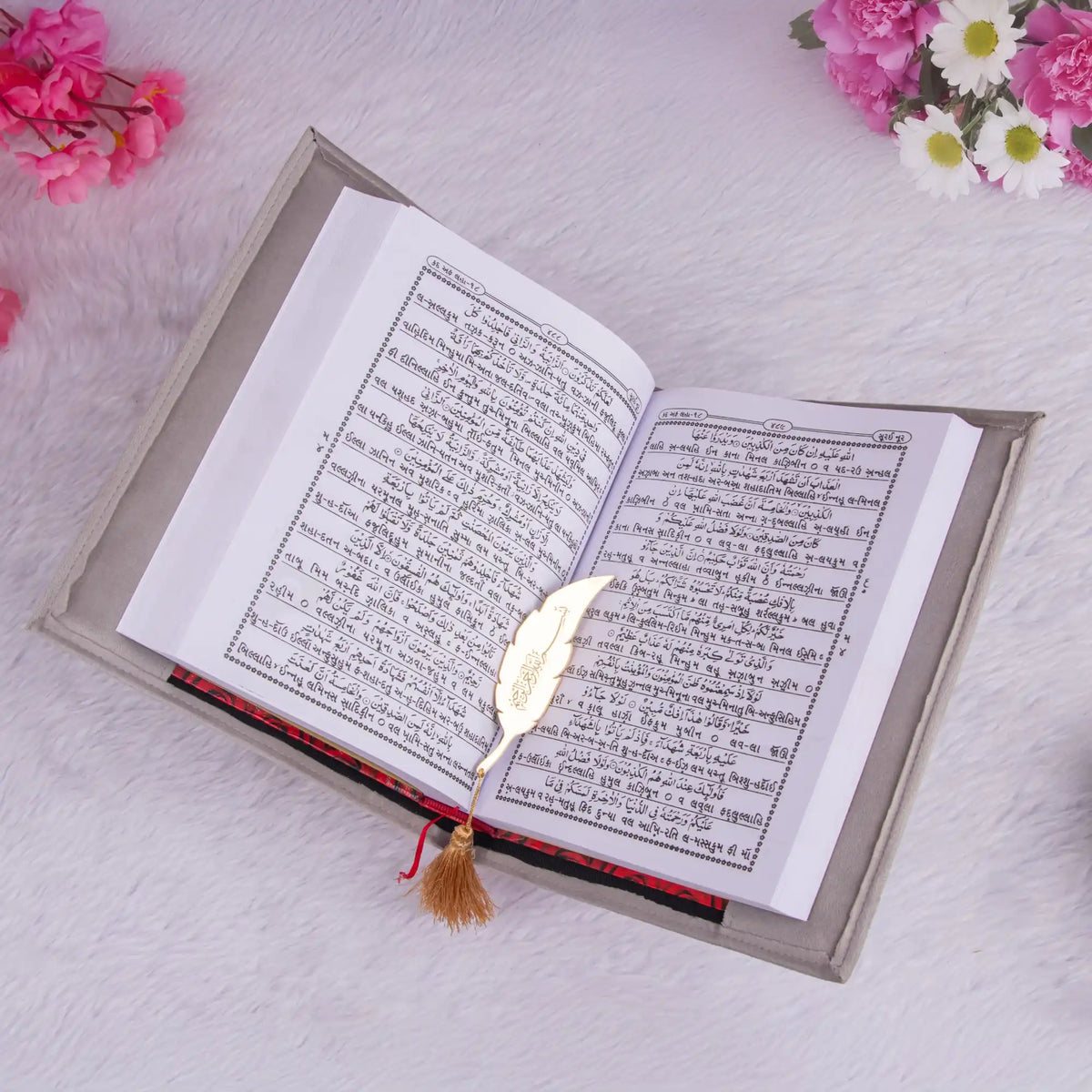 Open book with a decorative bookmark on a light surface with flowers around