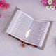 Open book with a decorative bookmark on a light surface with flowers around