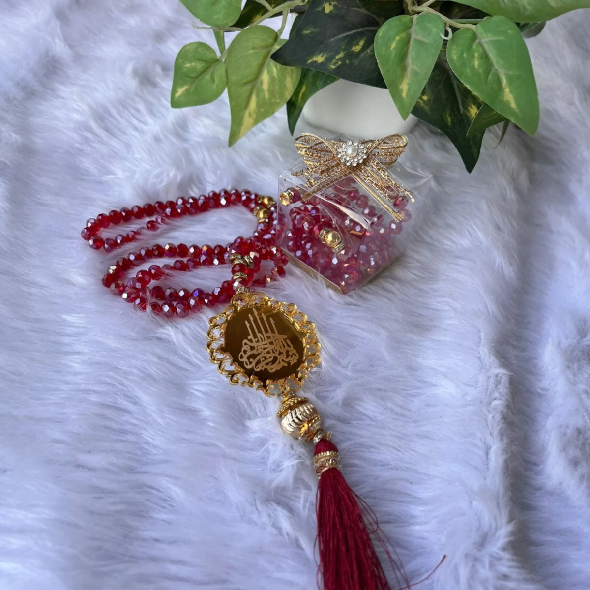 Elegant red 100 Beads Crystal Tasbeeh with gold calligraphy pendant and tassel, styled with gift box, ideal for Ramadan and Eid celebrations.