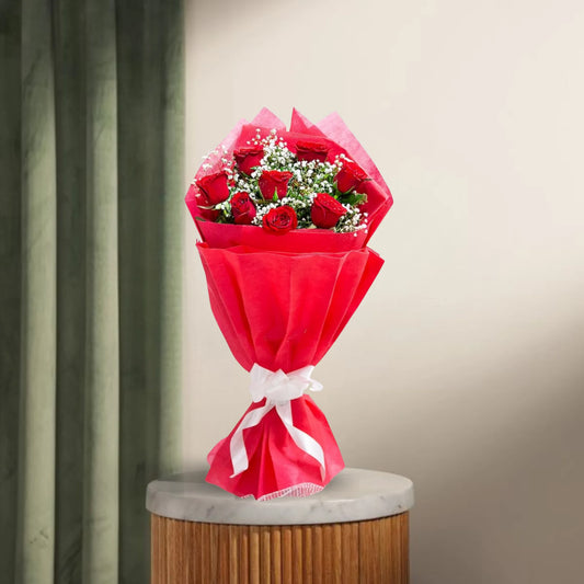 8 Red Roses Bouquet wrapped in red paper with white ribbon, displayed on a marble-top table. Romantic gift for anniversaries or Valentine's Day.