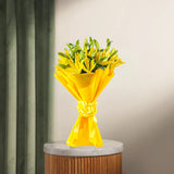 Asiatic Lilies Bunch - Lovely Flowers in bright yellow wrapping, displayed on a marble-top stand. Perfect for anniversaries or same day delivery.