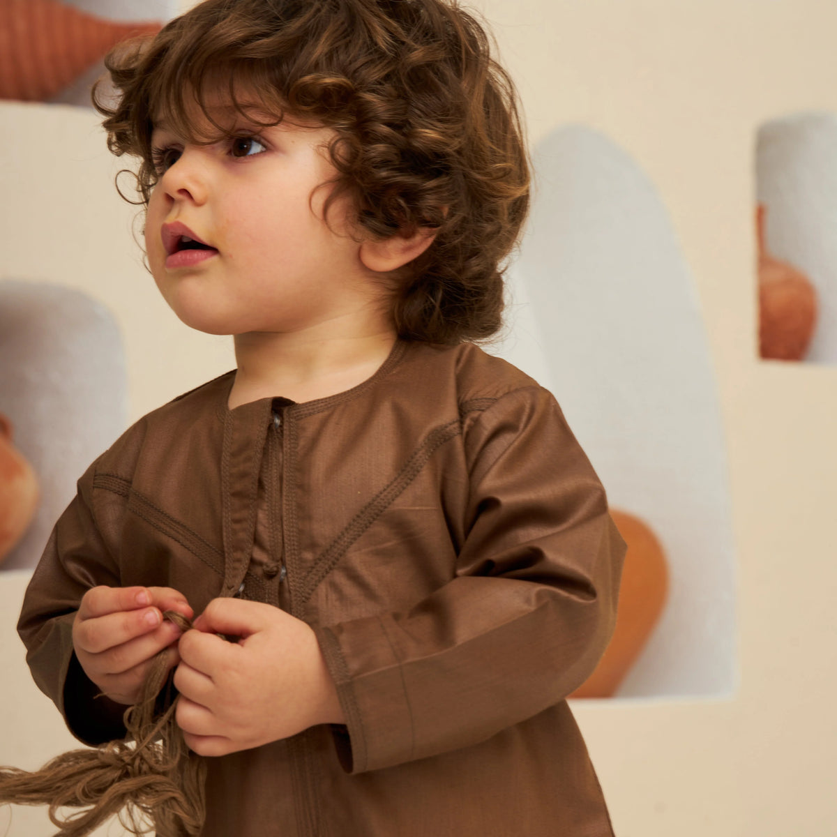 Close-up of baby boy wearing Brown Thobe Romper Boys - Baby Boys Thobe Romper, highlighting soft fabric and traditional embroidery detail.