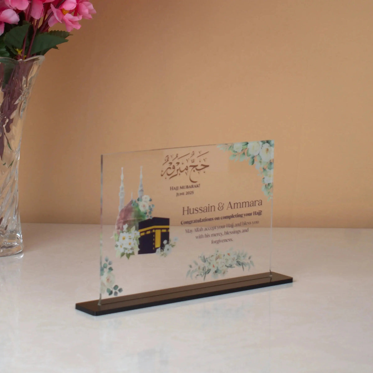 Labbaik-e-Haram Gifting Plaque featuring Kaaba and Masjid illustration, personalized with names and Hajj congratulatory message on clear acrylic.