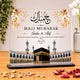 Hajj Mubarak decorative plaque with Islamic architecture design on a wooden surface.