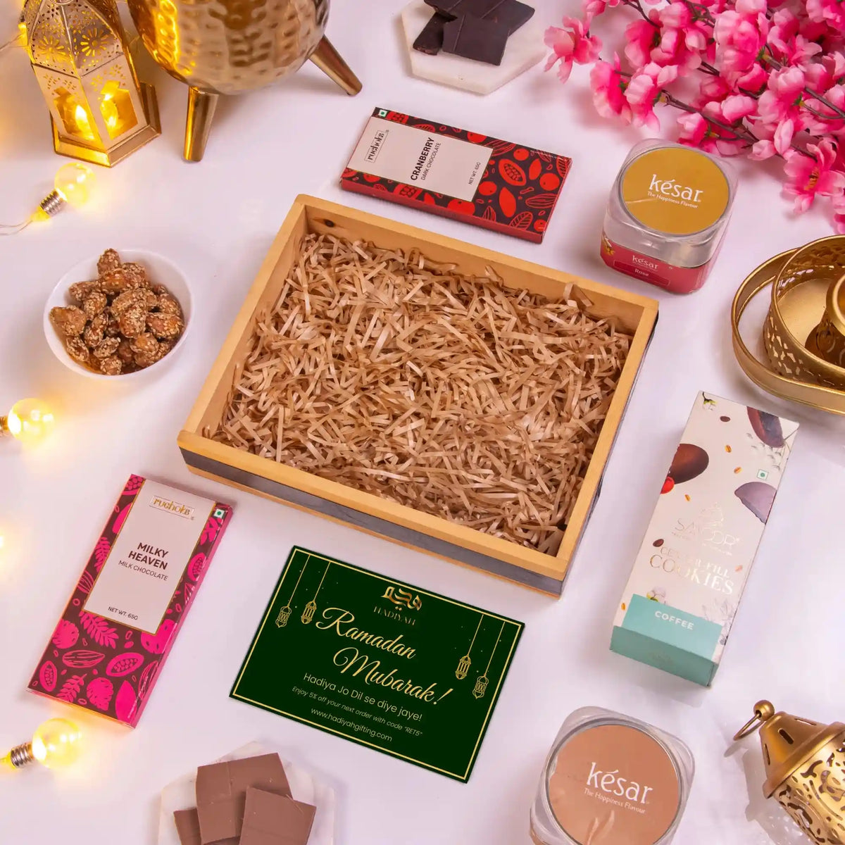 Gourmet gift set with chocolates, flowers, and a card on a white surface.