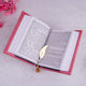 Open book with a gold feather bookmark on a light pink surface with pink flowers.