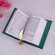 Open book with a gold leaf bookmark on a light gray surface with pink flowers.