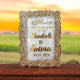 Decorative plaque with 'Shadab & Saima' and date on a wooden surface with a sunset background