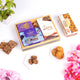 Unwrapped Velvet Bliss & Nut Hamper showcasing assorted almond cookies, hazelnut bites, and a purple velvet box in a premium wooden tray.