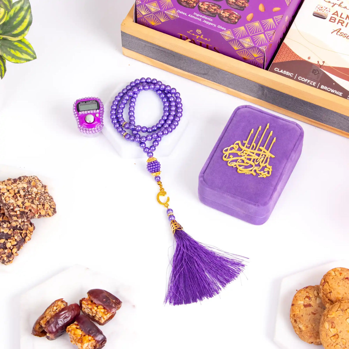 Purple prayer beads with tassel, purple decorative box, and cookies on a white surface.