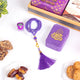 Purple prayer beads with tassel, purple decorative box, and cookies on a white surface.