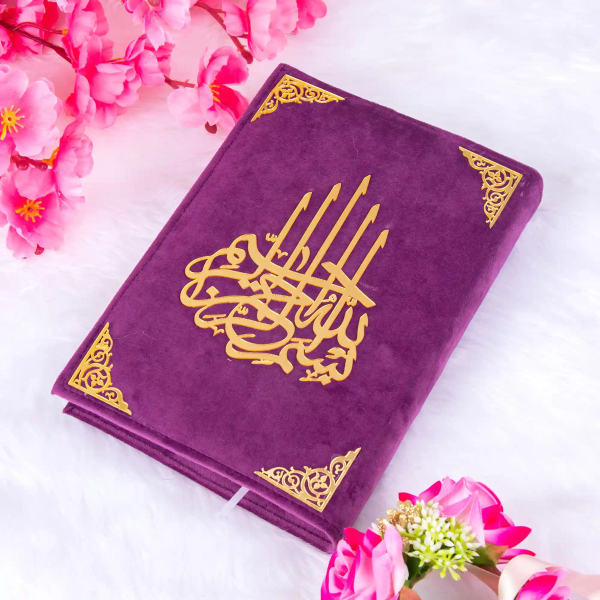 Elegant purple velvet Quran with gold detailing from the Butterfly Sawab-e-Jariya gift set, surrounded by pink flowers on white fur.