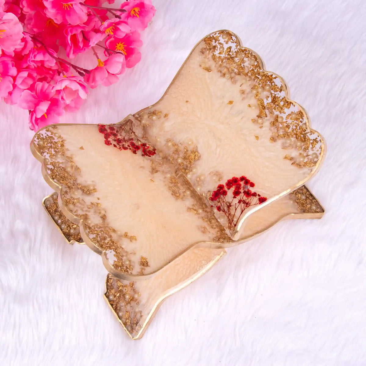 Decorative leaf-shaped plate with gold and beige finish, featuring red flowers, on a white background.
