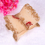 Decorative leaf-shaped plate with gold and beige finish, featuring red flowers, on a white background.