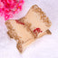 Decorative leaf-shaped tray with gold and beige finish on a white background with pink flowers.