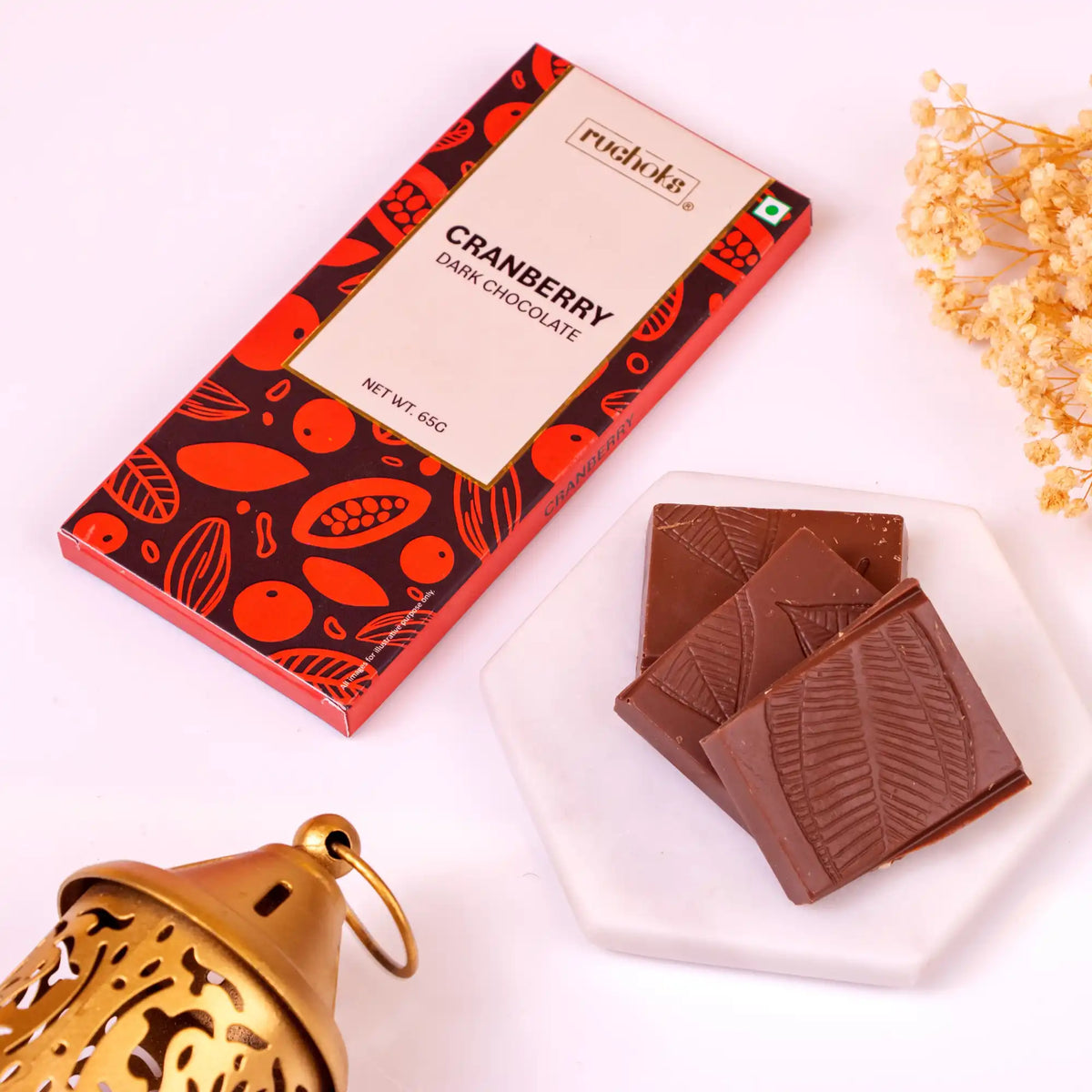 Ruchoks cranberry dark chocolate bar with leaf design pieces on a plate. Featured in Noor Al-Sweets & Serenity Hamper for Ramadan celebrations.